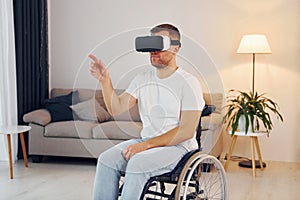 In VR glasses. Disabled man in wheelchair is at home