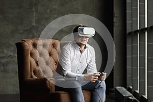 The VR headset design is generic and no logos, Man wearing virtual reality goggles watching movies or playing video games, dark ph
