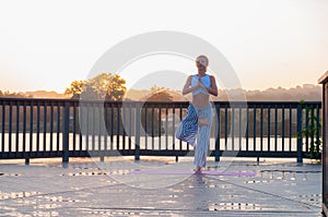 Vrikshasana pose. Young woman is doing yoga on the sunrise