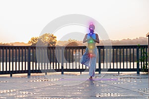 Vrikshasana pose. Young woman is doing yoga on the sunrise