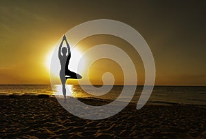 Vrikshasana tree pose from yoga by woman silhouette on sunset