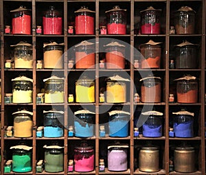 Vrious colorful dye in glass containers ion shelves in a paint shop