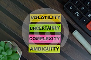 VUCA - Volatility Uncertainly Complexity Ambiguity write on sticky notes isolated on Wooden Table