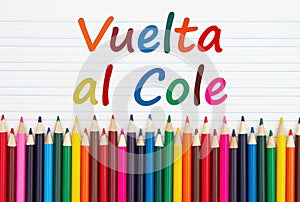 Vuelta al Cole message with color pencils crayons on vintage ruled line notebook paper