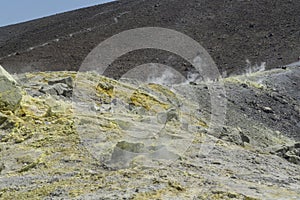 Vulcano trekking with fumaroles and a couple of touris walking on the ground path with big mountain photo