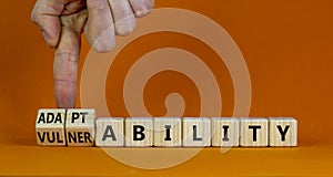 Vulnerability or adaptability symbol. Businessman turns cubes and changes words `vulnerability` to `adaptability`. Orange photo