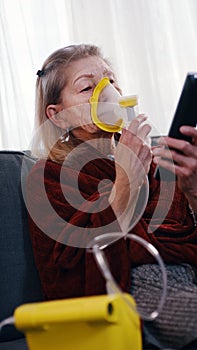 Vulnerable old woman in quarantine using oxygen inhaler and changing chanels on tv