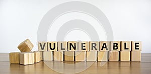 Vulnerable symbol. The word Vulnerable on wooden cubes. Beautiful wooden table, white background. Business and vulnerable concept