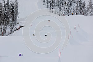 Young boy in mid-air jump in a slopestyle terrain park while his friends watching photo