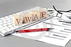 VWAP written on a wooden cube on the keyboard with chart on grey background