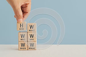 5W1H concept. Business framework and analysis. WHO WHAT WHERE WHEN WHY HOW Questions. Hand arranged wooden cubes block with photo