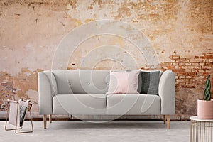 Wabi sabi living room interior with old shabby wall and trendy new couch with pastel pink and black pillows, real photo photo
