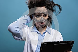 Wacky and silly looking crazy chemist with touchscreen tablet, puzzled by failed experiment report.