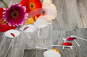 Wadded pads, sticks and cotton flowers on the wooden table against the gray wall. Flowers on a wooden background with wicker stick