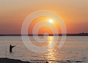 Wade fishing at sunrise with Asian man fishing spin casting at Lavon Lake near Dallas, Texas, USA