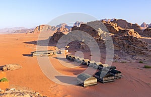 Wadi Rum desert, Jordan. Beautiful aerial view of bedouin camp at sunset from above with tents lined up and red rock formations