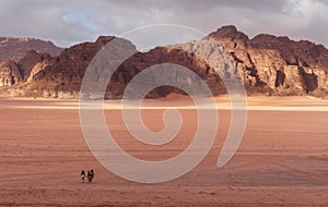 Wadi Rum desert landscape in sunrise, with family riding camels. Famous travel and adventure destination in Jordan