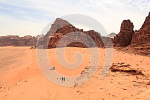 Wadi Rum desert panorama with dunes, mountains, tourists and Pickup trucks, Jordan