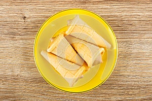 Wafer horns with cream in saucer on wooden table. Top view