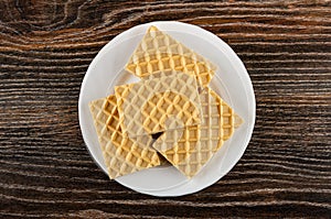 Wafers with filling in white plate on wooden table. Top view