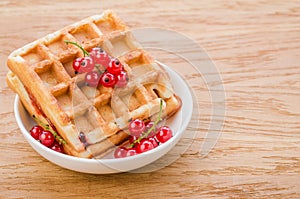 wafers with red berries in a white plate on a wooden background/wafers with red berries in a white plate on a wooden background.