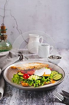 Waffle bread sandwich with poached egg and vegetables on a plate on the table vertical view