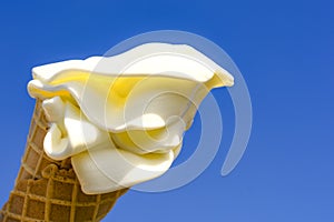 Waffle cone with creamy ice cream in the sun on a background of blue sky