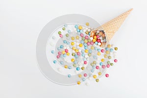 Waffle cone and heap colorful candy on white background from above. Flat lay style.