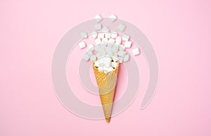 Waffle cone with white mini marshmallows on a pink background