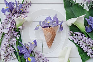 Waffle cone with wisteria, irises, callas flower on pink background. Flat lay, top view floral background.