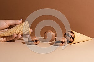 Waffle cones with brown chocolate macaroons on beige background. Sweet food. Tasty desert. Homemade meal. Delicious food. Space