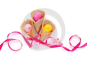 Waffle Cones with Easter eggs and ribbon on white background. Space for text. Top view