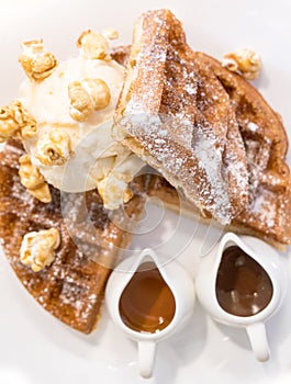 Waffle dressed with pop corn, ice cream and chocolate and caramel sauces