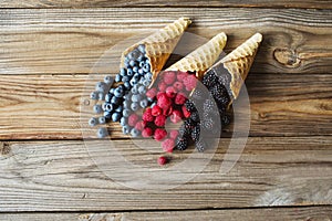 Waffle with fresh berries. Berries. Raspberries, blackberries, blueberries in waffle cones on a gray abstract background.