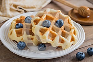 Waffle with fresh blueberry on plate and honey dipper