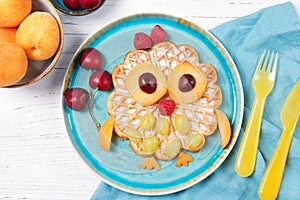 Waffle with fruits and berries in the shape of cute owl with balloons, food for kids idea, top view