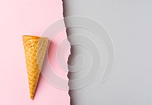 Waffle ice cream cone with on duotone pink grey paper background with torn frazzle edge. Styled image mockup flyer poster template