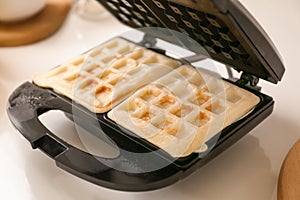 Waffle iron with fresh wafers on kitchen table