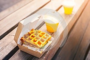 Waffle sandwich burger with orange juices at outdoors street food cafe. Fastfood eatery concept