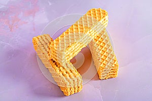 Waffle shaped like a letter displayed on a paper towel next to a regular waffle