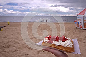 Waffle with strawberries and cream on the beach