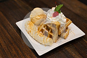 Waffle topped with ice cream , banana and wipe cream