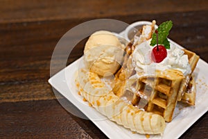 Waffle topped with ice cream , banana and wipe cream