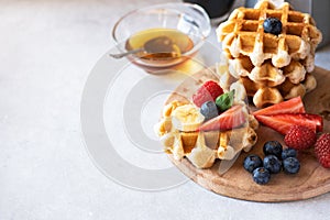 Waffles with berries and honey and coffee on a wooden board. Close up and copy space. Breakfast or brunch concept