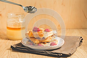 waffles with berries in plate poured by honey from a spoon/waffles with berries in plate poured by honey from a spoon on a wooden