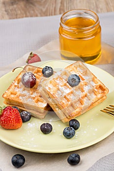 Waffles with berries on wooden background