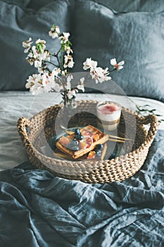 Waffles with blood orange and blueberries, rose latte in glass and blooming flower