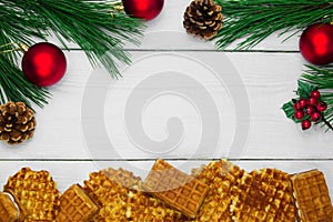 Waffles and branch christmas tree and red ball with cone on white wooden vintage background