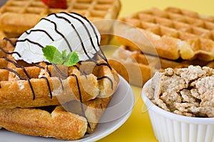 Waffles with chocolate sauce, ice cream and mint on yellow background