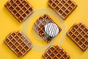 Waffles with chocolate sauce, ice cream and mint on yellow background